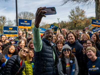 Sen. Raphael Warnock takes a selfie with supporters at a campaign rally outside the Democratic Party North Fulton headquarters on November 19, 2022, in Sandy Springs, Georgia.