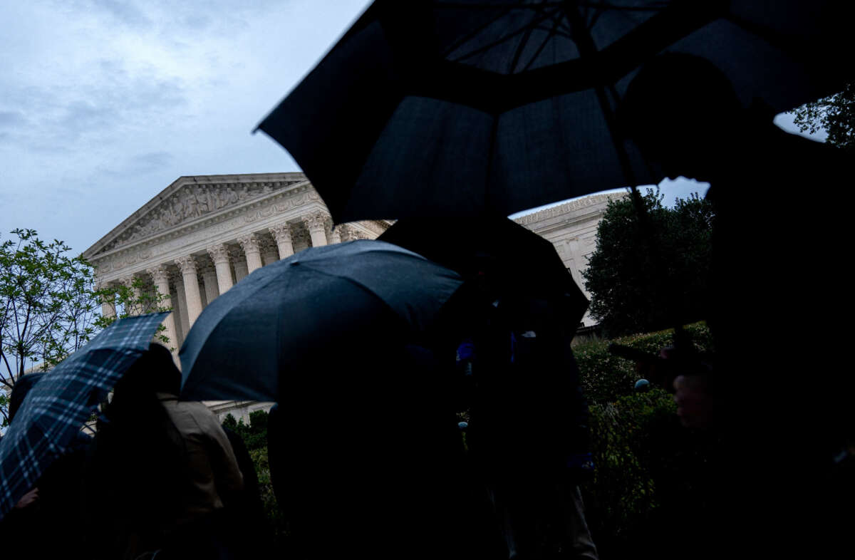 People hold umbrellas while standing in line outside the Supreme Court building in Washington, D.C., on October 3, 2022.