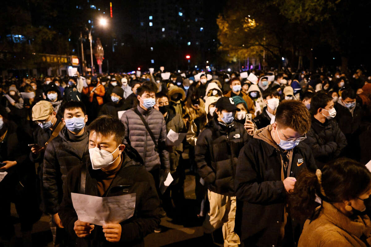 Demonstrators march along a street during a rally for the victims of a deadly fire as well as a protest against China's harsh COVID-19 restrictions, in Beijing on November 28, 2022.