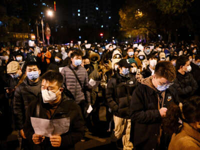 Demonstrators march along a street during a rally for the victims of a deadly fire as well as a protest against China's harsh COVID-19 restrictions, in Beijing on November 28, 2022.