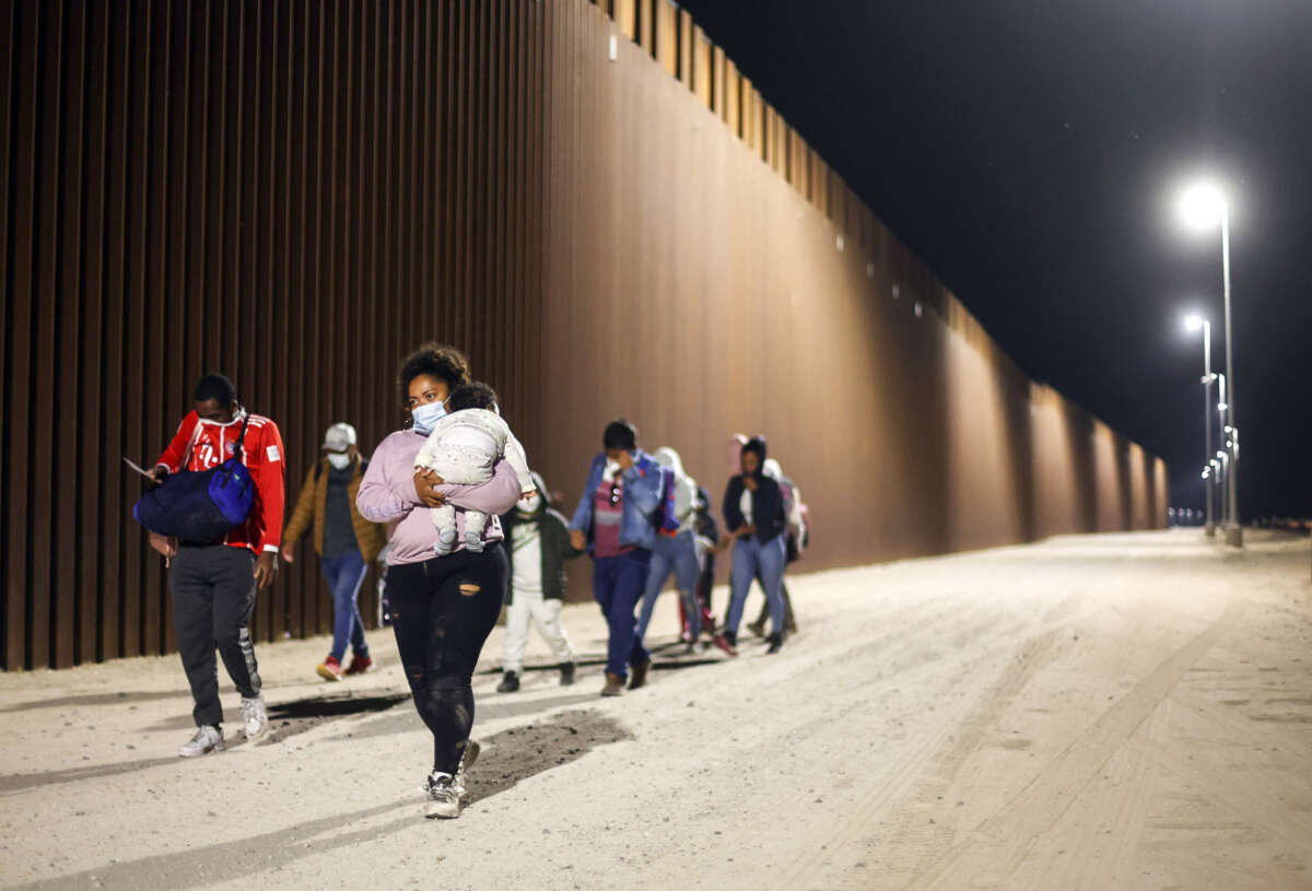 Immigrants walk along the U.S.-Mexico border barrier in the early morning hours on their way to be processed by the U.S. Border Patrol after crossing from Mexico, on May 23, 2022, in Yuma, Arizona.