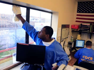 Prison janitor Christopher Britton cleans window in an office at the California Correctional Center December 3, 2014, in Susanville, California.