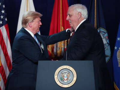 West Virginia Governor Jim Justice shakes hands with Donald Trump at a podium