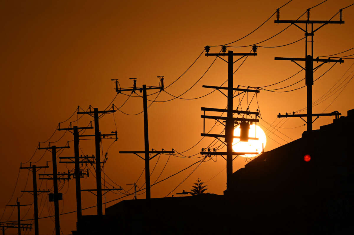 The sun sets behind power lines near homes in Los Angeles, California on September 6, 2022.