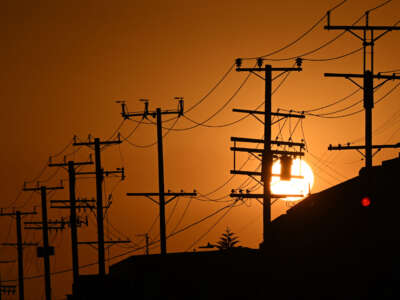 The sun sets behind power lines near homes in Los Angeles, California on September 6, 2022.