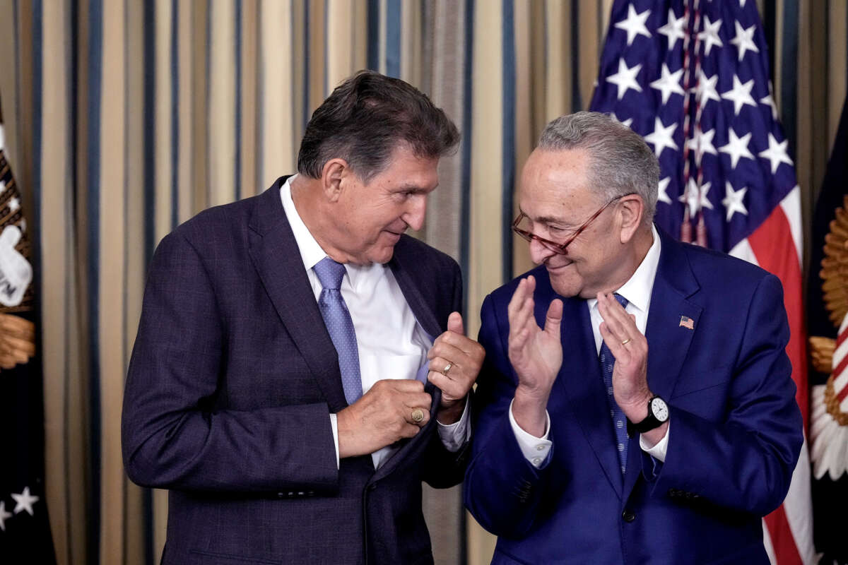 Sen. Chuck Schumer claps while speaking to Sen. Joe Manchin