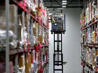 A worker on a lift wearing a safety harness retrieves an item for an order from the top shelf inside the million-square foot Amazon distribution warehouse in Fall River, Massachusetts, on March 23, 2017.