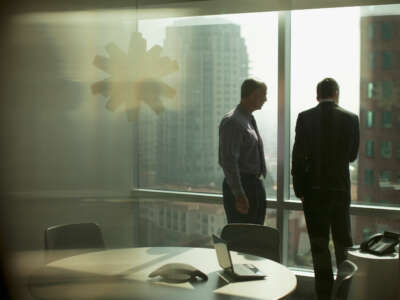 Two businessmen look down from highrise office window