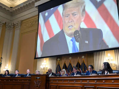 Donald Trump is seen on a projector behind the January 6th commission