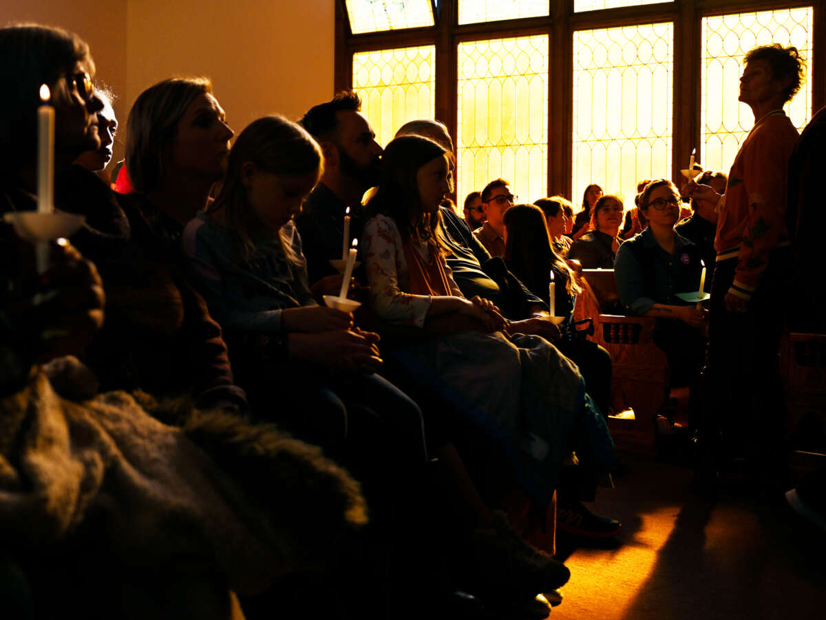 People holding candles pray during a vigil inside of a church