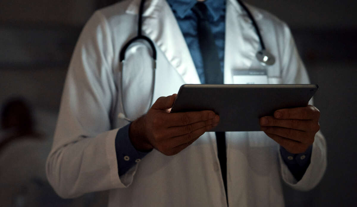 Doctor in a dark room lit by tablet he is looking at