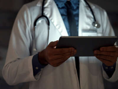 Doctor in a dark room lit by tablet he is looking at
