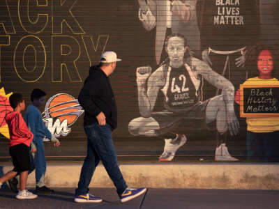 A man and two boys look at a mural featuring Brittney Griner
