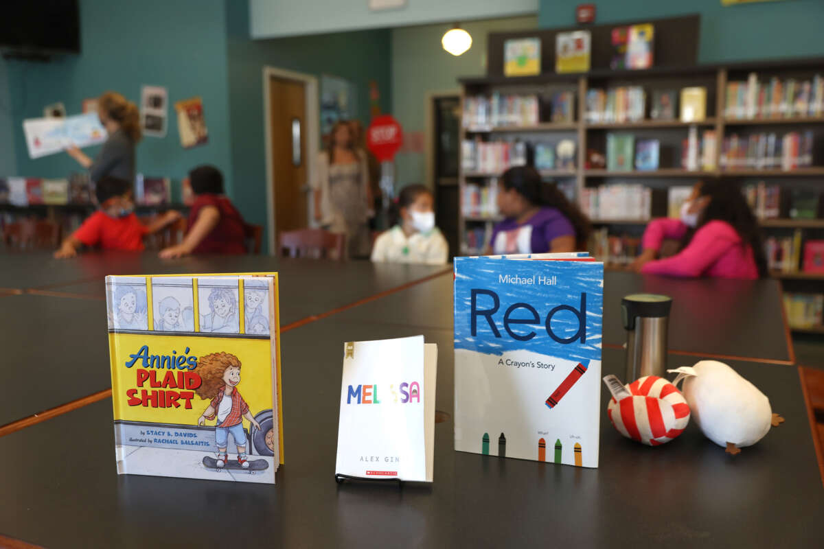 Three books are displayed on a library table