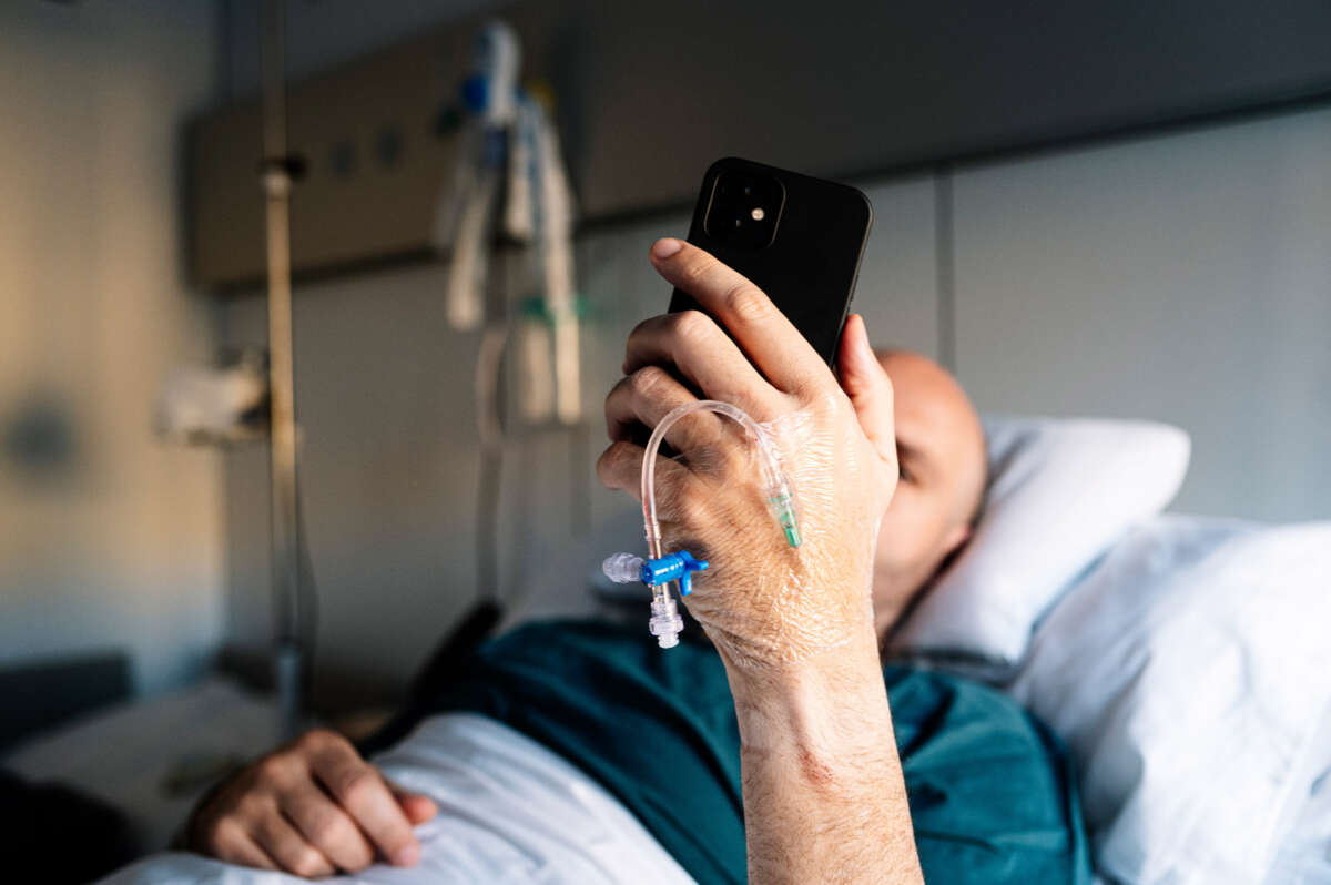 Patient in hospital bed checks phone