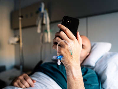 Patient in hospital bed checks phone