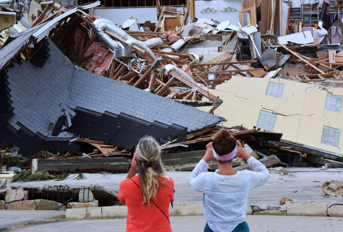 People take pictures of a home that collapsed onto the beach due to the storm surge and resulting erosion caused by Hurricane Nicole on November 11, 2022, in Wilbur-By-The-Sea, Florida.