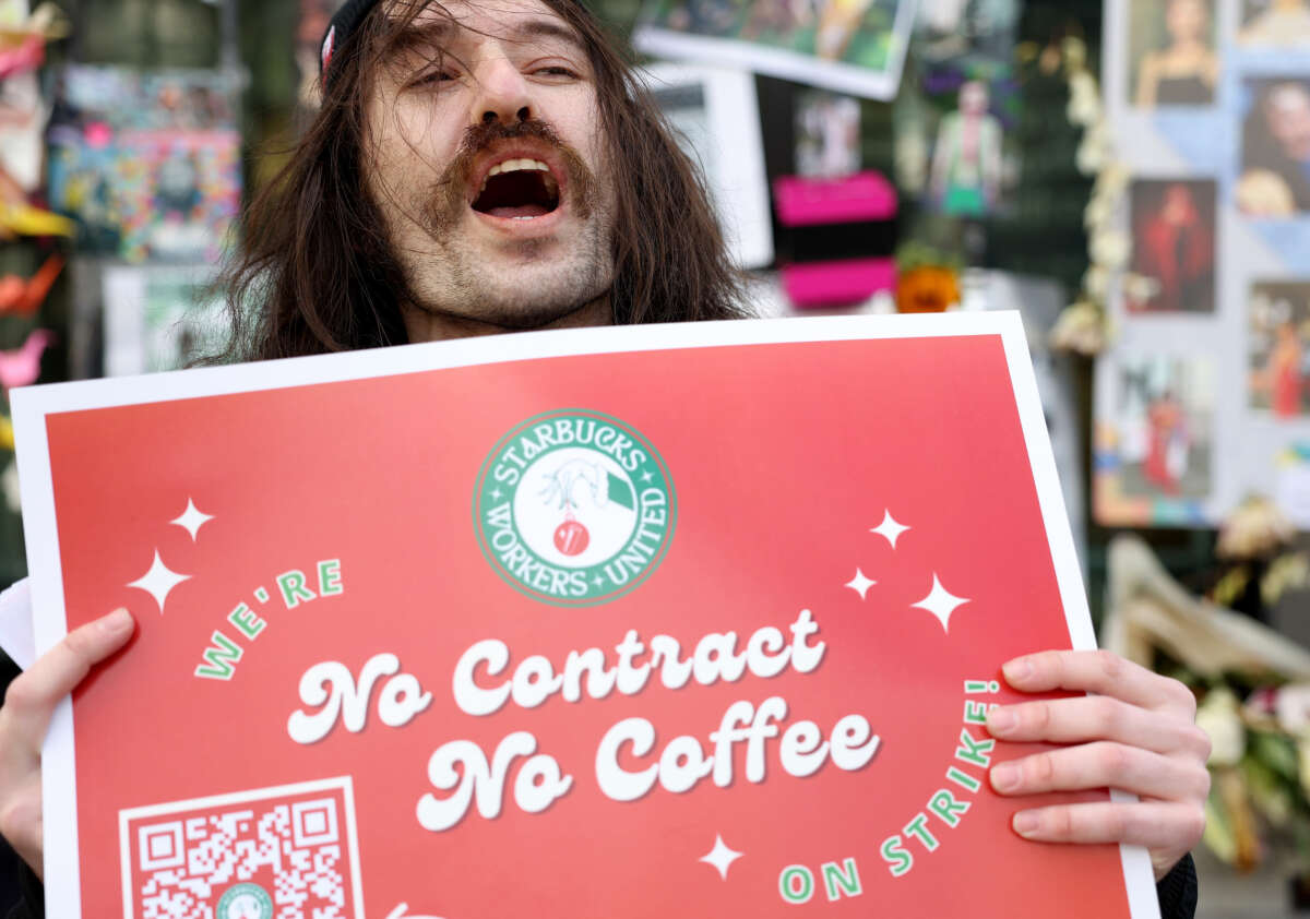 Striking Starbucks worker Kyle Trainer holds a sign outside of a Starbucks coffee shop during a national strike on November 17, 2022, in San Francisco, California.