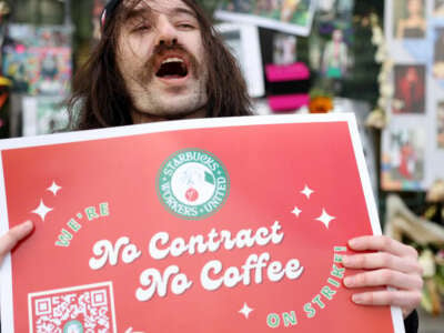 Striking Starbucks worker Kyle Trainer holds a sign outside of a Starbucks coffee shop during a national strike on November 17, 2022, in San Francisco, California.
