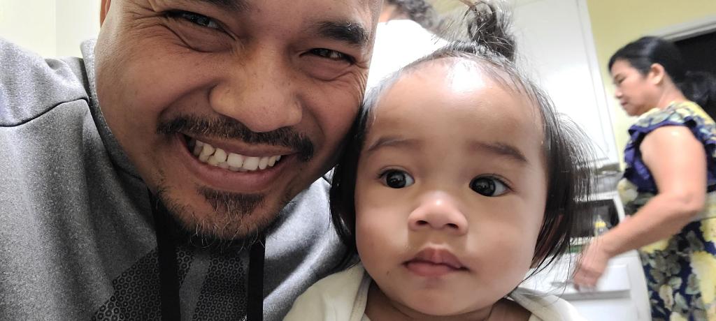 A man smiles next to his very adorable baby