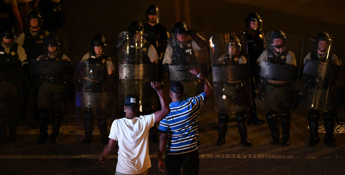 Protesters raise their fists in front of police in riot gear during a protest against police brutality in Rock Hill, South Carolina on June 24, 2021.