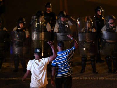 Protesters raise their fists in front of police in riot gear during a protest against police brutality in Rock Hill, South Carolina on June 24, 2021.