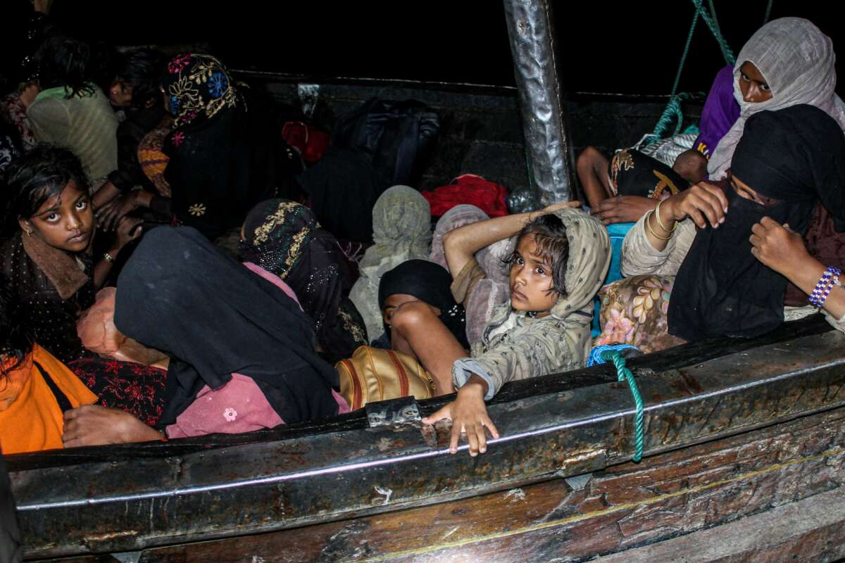 Rohingya refugees sit on a wooden boat as Indonesian officials conduct evacuation at the Krueng Geukueh port in Lhokseumawe, Aceh, Indonesia, on December 31, 2021.