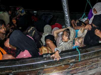 Rohingya refugees sit on a wooden boat as Indonesian officials conduct evacuation at the Krueng Geukueh port in Lhokseumawe, Aceh, Indonesia, on December 31, 2021.