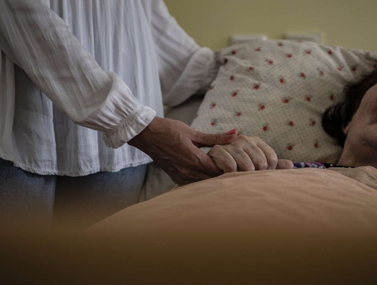 A woman holds the hand of a person in need of care in a nursing home in Berlin, Germany on May 25, 2022.