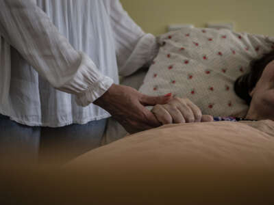 A woman holds the hand of a person in need of care in a nursing home in Berlin, Germany on May 25, 2022.