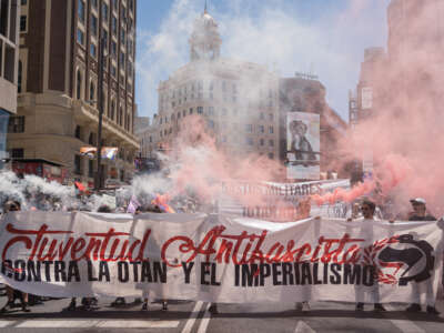 Anti-fascist protesters hold a banner and red smoke flares during a demonstration against NATO in Madrid, Spain on June 26, 2022.