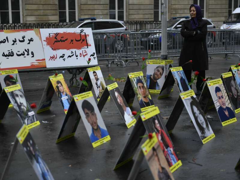 A demonstrator stands next to placards with portraits of the victims of Iran's repression, near the French National Assembly in Paris, France, on December 6, 2022.