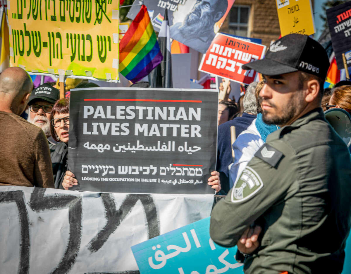 An Israeli protestor holds a sign that says "Palestinian Lives Matter" outside the Knesset