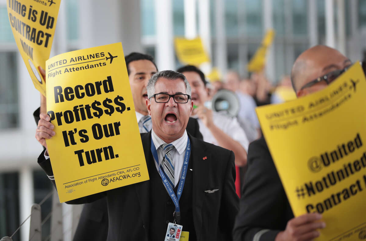 A United Airlines employee holds a sign that says "Record Profits. It's Our Turn."