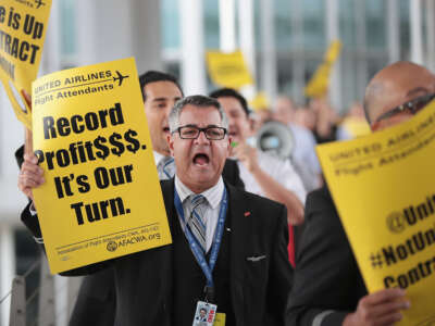 A United Airlines employee holds a sign that says "Record Profits. It's Our Turn."