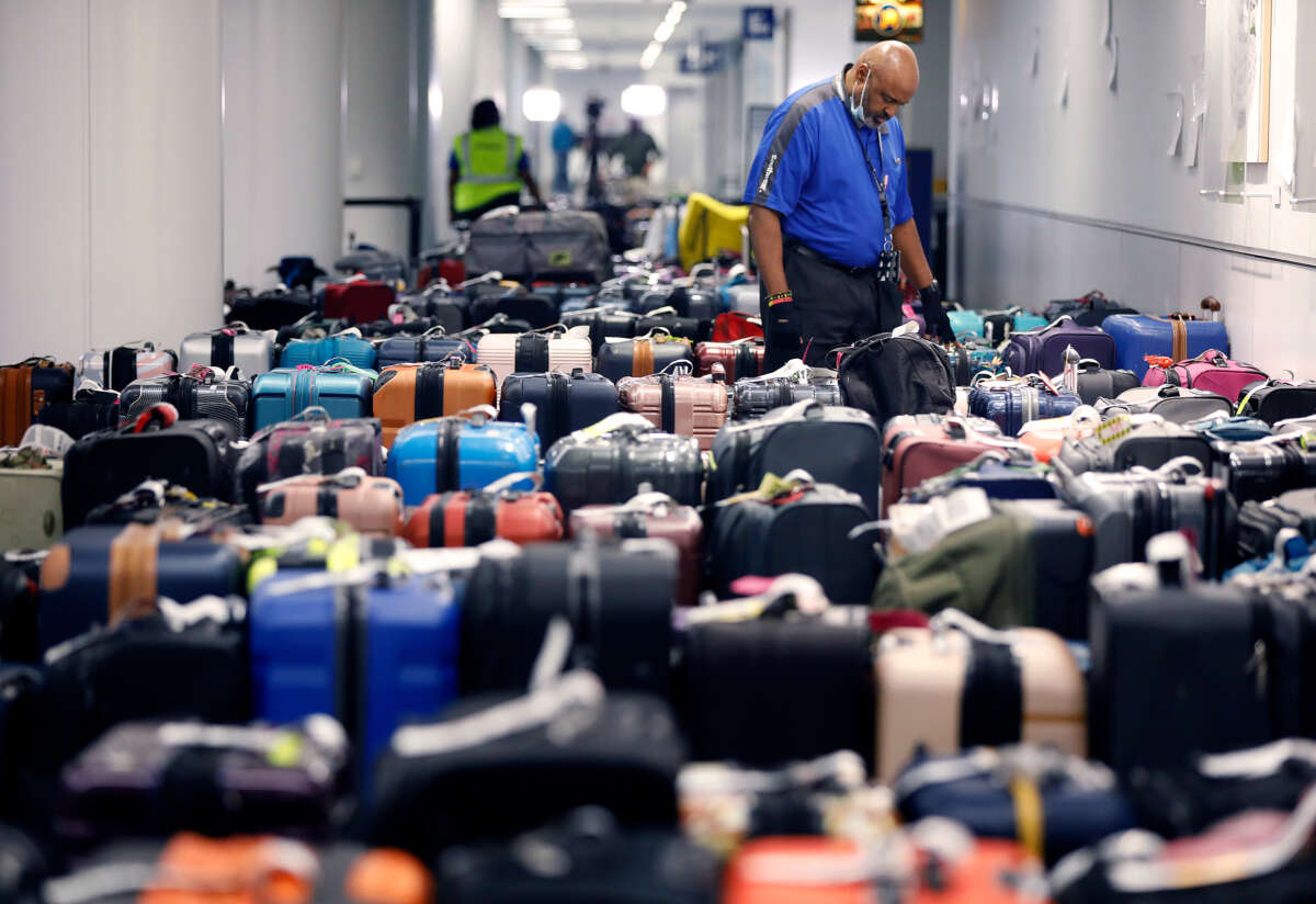 An overwhelmed-looking Southwest Airlines luggage handler looks at the dozens of lost suitcases surrounding him
