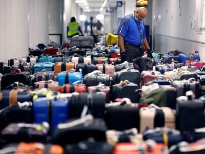 An overwhelmed-looking Southwest Airlines luggage handler looks at the dozens of lost suitcases surrounding him