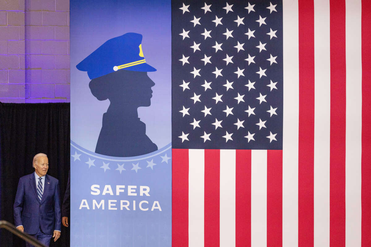 Joseph Robinette Biden emerges from behind a banner bearing the silhouette of a cop and the words "SAFER AMERICA"