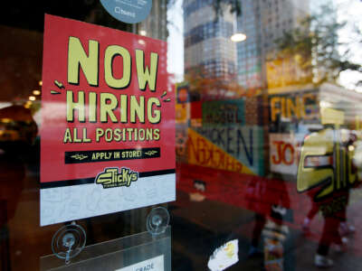 A Now Hiring sign is displayed on a shopfront on October 21, 2022, in New York City.