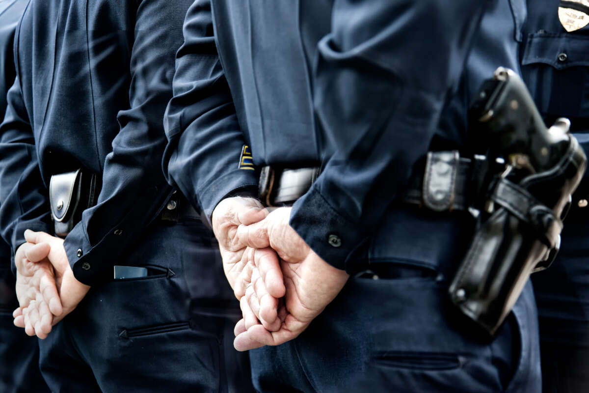 Police with hands behind back, gun in holster