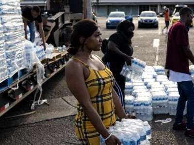 Aelicia Hodge, center, helps hand out cases of bottled water at a Mississippi Rapid Response Coalition distribution site on August 31, 2022, in Jackson, Mississippi.
