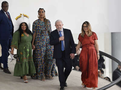 Luiz Inácio Lula da Silva walks alongside his wife accompanied by others, including new Minister of Indigenous Peoples Sonia Guajajara wearing a traditional headdress