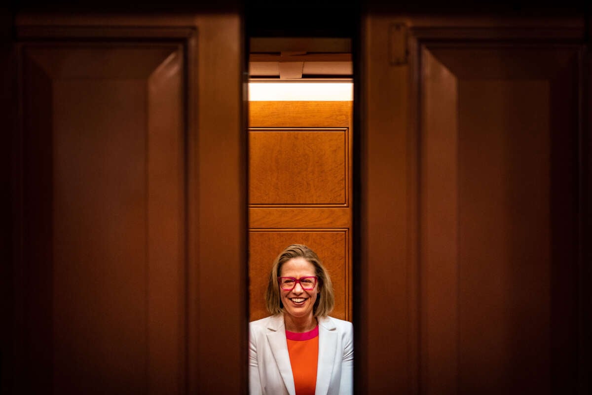 Sen. Kyrsten Sinema smiles while talking to reporters after leaving the Senate chamber on Capitol Hill on November 16, 2022, in Washington, D.C.