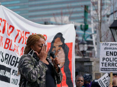 A woman weeps while speaking into a microphone on stage during a rally