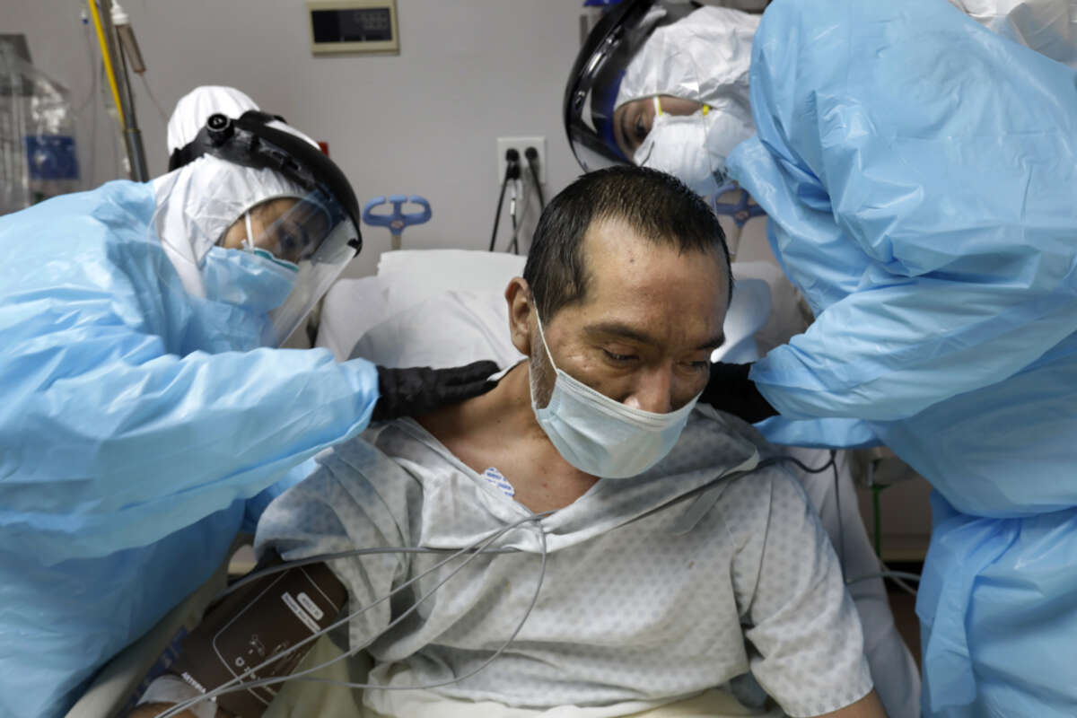 COVID unit nurse Anita Pedy (left) and medical student volunteer Alan Araiza (right) check bruises on the back of COVID patient Melquiades Cervantes at United Memorial Medical Center in Houston, Texas, on May 6, 2020.