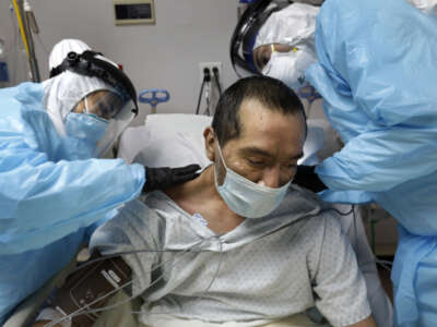 COVID unit nurse Anita Pedy (left) and medical student volunteer Alan Araiza (right) check bruises on the back of COVID patient Melquiades Cervantes at United Memorial Medical Center in Houston, Texas, on May 6, 2020.