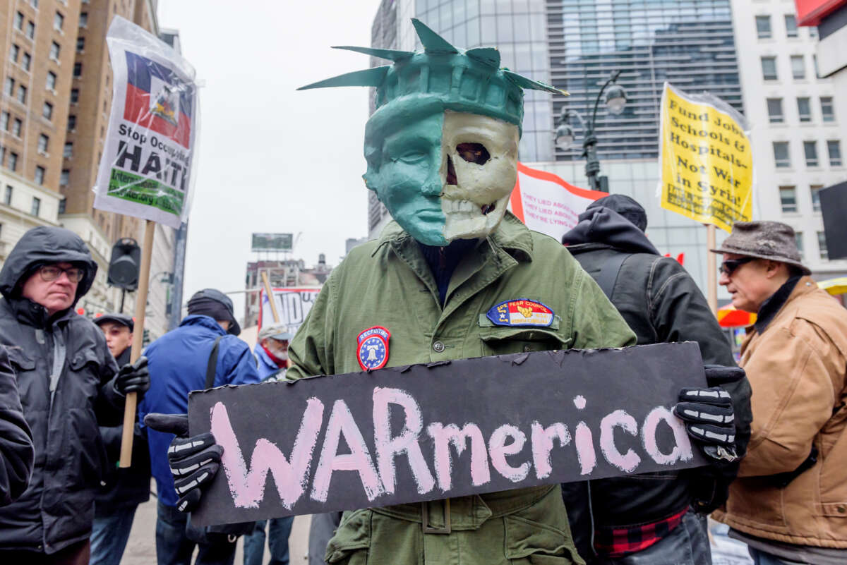 A protester is holding a sign that reads "WARmerica" and is dressed in a jumpsuit and a mask with half the face modeled on the statue of liberty and half the face a skull. Hundreds took to the streets as antiwar and social justice groups organized a demonstration against the US bombing of Syria and opposing endless U.S. wars on April 15, 2018, in New York City.