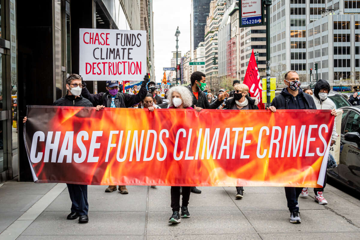 Protestors march through New York City with a banner that says "Chase Funds Climate Crimes"