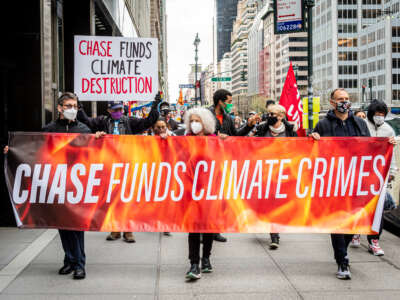 Protestors march through New York City with a banner that says "Chase Funds Climate Crimes"