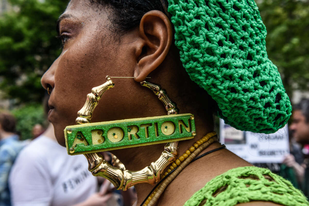 A woman at an abortion rally wears earrings that say "abortion"